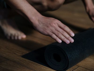 Roll of a purple yoga mat on a wooden floor.